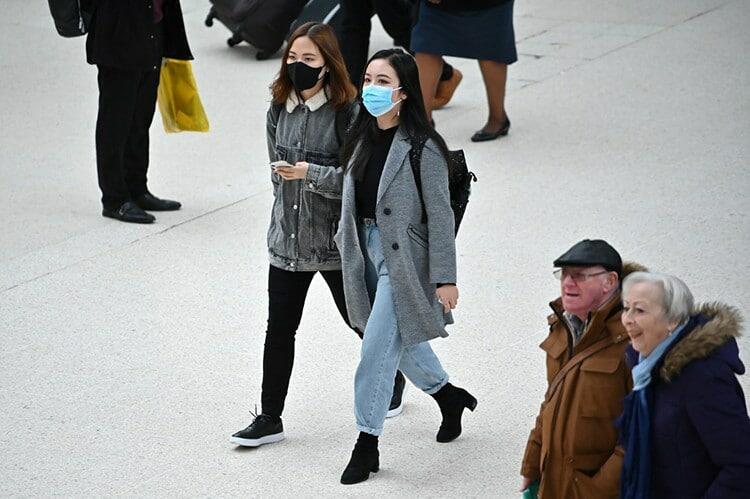 Hai cô gái gốc Á đeo khẩu trang đi qua sân ga Victoria ở trung tâm London, Anh hôm 3/3. Ảnh: AFP